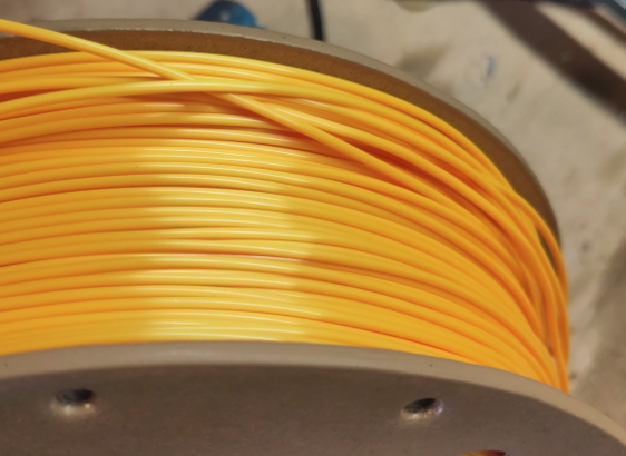 A spool of plastic filament with badly spooled filament.