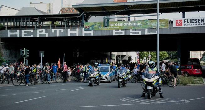 cyclists getting ready for the start of the bike protest underneath the railway bridge. Police cars and motorbikes are waiting as well.