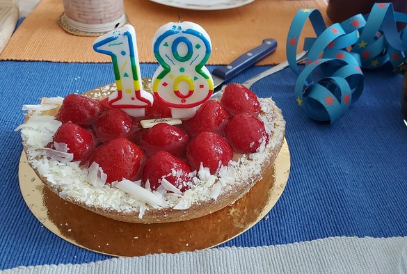 Geburtstagstorte mit Erdbeeren, darauf zwei Kerzen, die zusammen die Zahl 18 ergeben