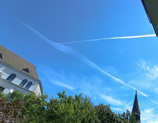 Wolken vor blauem Himmel, ein Gründerzeithaus mit Schieferdach, Bäume, Kirchturm