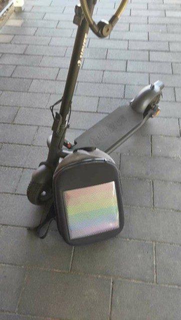 An electric scooter with a backpack showing a rainbow