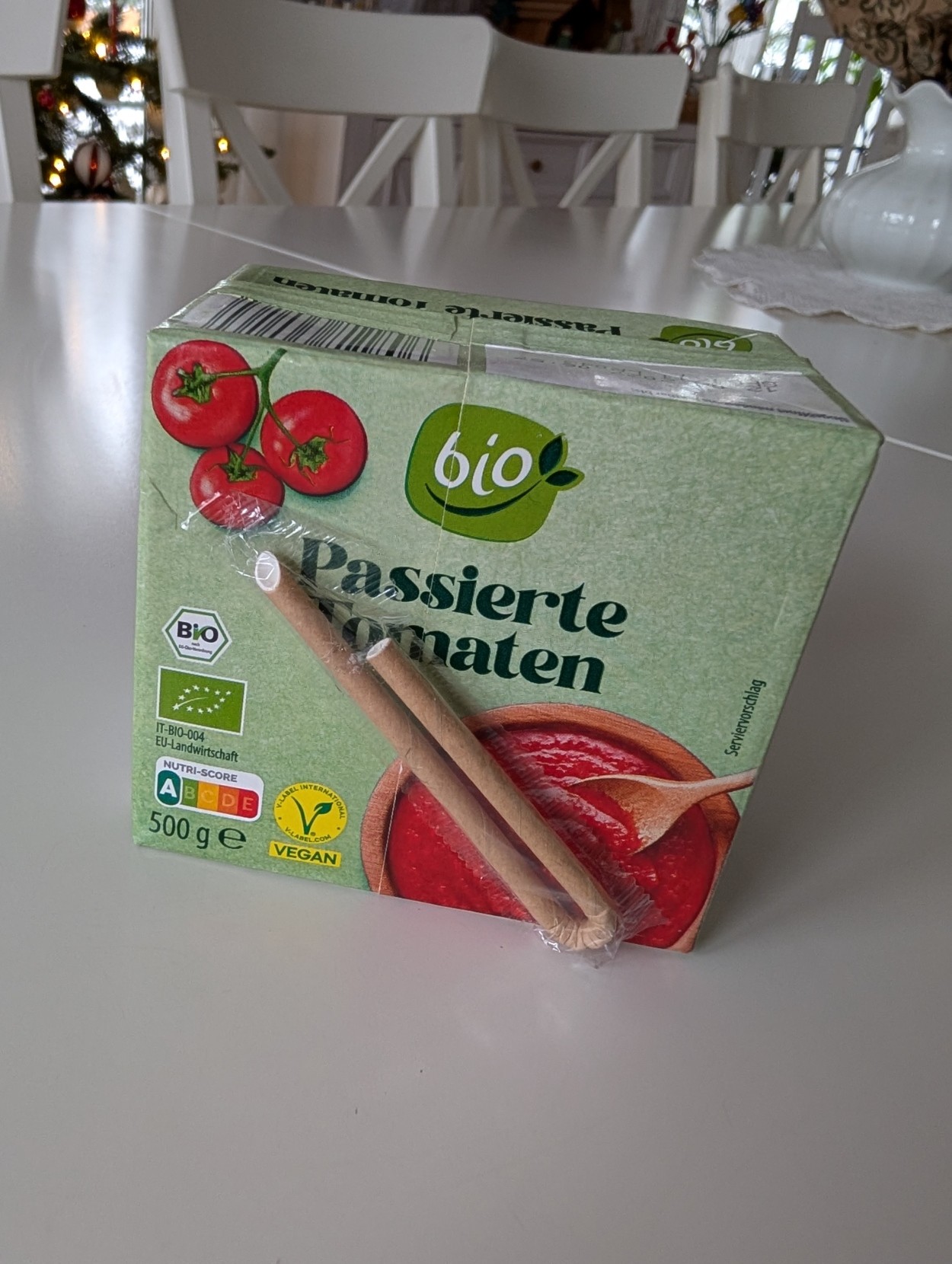 Ein Foto einer Packung passierte Tomaten, daran klebt ein kleiner Strohhalm, wie man das von Durstlöscher und anderen Getränkeboxen kennt.